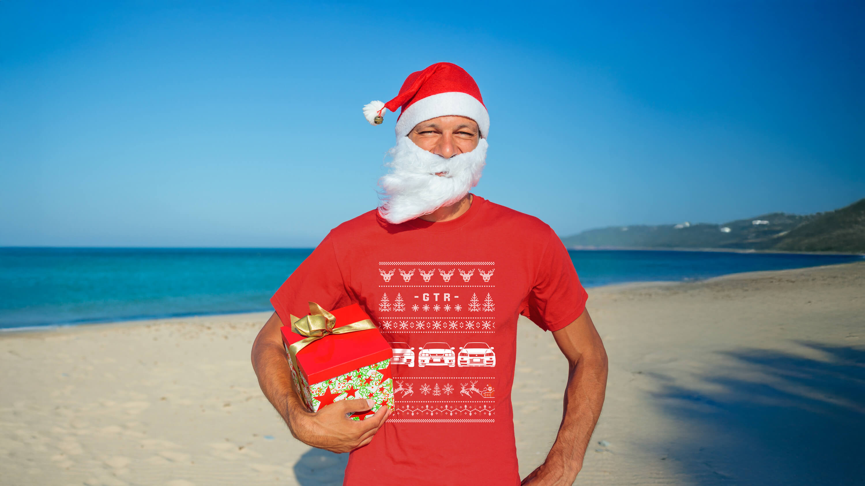 Man wearing a Santa hat and red Nissan GTR  Christmas t-shirt on a beach